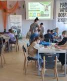 Grupa dzieci przy stołach maluje bawełniane torby.