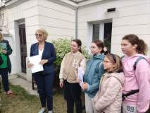 Dyrektor Książnicy Płockiej wręcza dyplom grupie dzieci uczestniczącej w grze miejskiej.