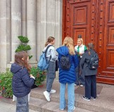 Grupa dzieci przed drzwiami płockiej katedry rozwiązuje kolejne zadanie.
