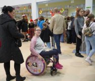 Uczennica poruszająca się na wózku inwalidzkim, odwiedzająca kramiki pod opieką mamy.