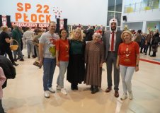 Organizatorzy kiermaszu na wspólnym zdjęciu. W tle przybyli Goście. 