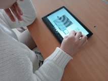foto_12 Uczennica przy ławce szkolnej dokonuje na tablecie symulacji fizycznych dotyczących dźwięków