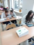 foto_8  Trzy uczennice siedzące przy łwakach szkolnych, dokonujące na tabletach symulacje fizyczne