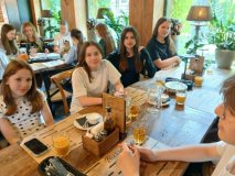 Przy dwóch restauracyjnych stołach siedzą uczestnicy Koła SU, wszyscy w pogodnych nastrojach.