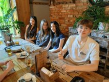 Czwórka uczestników SU przy restauracyjnym stole, każdy uśmiechnięty, a wśród nich chłpiec z uniesionym do góry kciukiem.