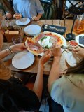 Zbliżenie na troje uczniów, którzy częstują się kolorową pizzą.