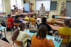 Sala lekcyjna. Uczniowie klasy czwartej siedząc w ławkach słuchają mini – wykładu o bezpieczeństwie w sieci: „Jak się nie zaplątać w sieci?”. Zajęcia prowadzi - Pani Marlena Szymczak, profilaktyk z Komendy Miejskiej Policji w Płocku.