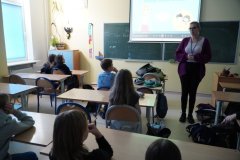 Sala lekcyjna. Uczniowie klasy czwartej siedząc w ławkach słuchają mini – wykładu o bezpieczeństwie w sieci: „Jak się nie zaplątać w sieci?”. Zajęcia prowadzi - Pani Marlena Szymczak, profilaktyk z Komendy Miejskiej Policji w Płocku.