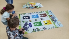Dzieci uczą się przy użyciu maty edukacyjnej, jak segregować odpady.