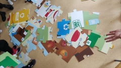 Dzieci układają mega puzzle tematycznie związane z segregacją odpadów.