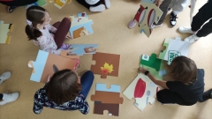 Dzieci układają mega puzzle tematycznie związane z segregacją odpadów.