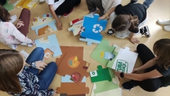 Dzieci układają mega puzzle tematycznie związane z segregacją odpadów.