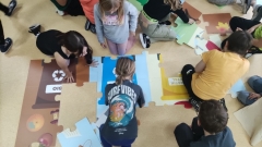 Dzieci układają mega puzzle tematycznie związane z segregacją odpadów.