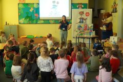 Świetlica szkolna. Uczniowie klas pierwszych siedząc na dywanie, oglądają kolorowy model z symulacją działania sieci kanalizacyjnej.