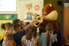 Świetlica szkolna. Uczniowie klas pierwszych żegnając się z maskotką Wydrą Lutrą – „przybijają jej piatkę”.