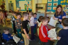 Świetlica szkolna. Uczniowie klas pierwszych ustawiają się do wyjścia. Na pożegnanie otrzymują w prezencie od prowadzącej kampanię, białe worki z tkaniny z nadrukiem maskotki Wydry Lutry.