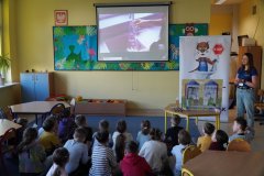 Świetlica szkolna. Uczniowie klas drugich siedząc na dywanie, uczestniczą w lekcji ekologicznej, oglądają film edukacyjny.
