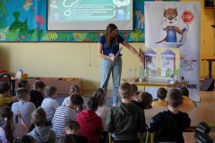 Świetlica szkolna. Uczniowie klas drugich siedząc na dywanie, słuchają prowadzącej kampanię Pani Aleksandry Pokorskiej i oglądają kolorowy model pokazujący, skąd bierze się woda w płockich kranach.