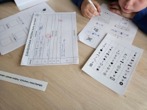 Dzieci odszyfrowują za pomocą tablicy zaszyfrowane wiosenne słowa.
