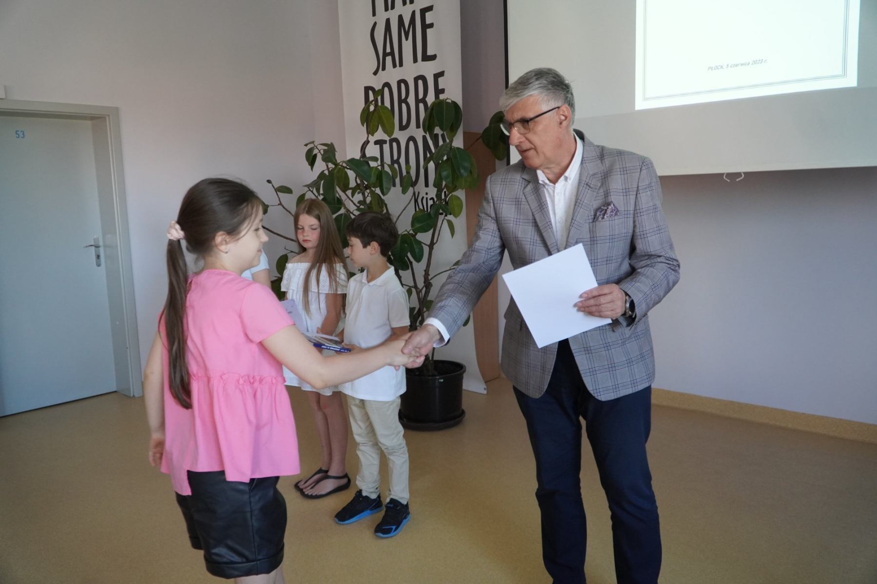 Pan Dyrektor wręcza dyplom za udział w Konkursie Ortograficznym uczennicy klasy trzeciej.