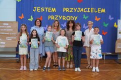 21.	Przedstawiciele klas otrzymują dyplomy „Wzorowego Przyrodnika” za aktywny udział w przygotowanym przedsięwzięciu. Wspólnie z organizatorami konkursu pozują do pamiątkowego zdjęcia. 