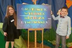 Dwoje uczniów z naszej szkoły – Kornelia i Dominik pozują przy kolorowej planszy „Chotomek” wyłania Mistrza Rymowania.