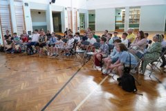 Uczestnicy konkursu wraz z opiekunami siedzący na sali gimnastycznej.