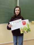 Uczennica Ewa Zakrzewska pozuje z nagrodą i swoją zwycięską pracą w szkolnym konkursie na najlepszy rebus.