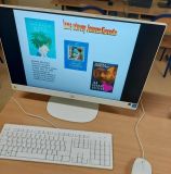 Zbliżenie na monitor komputera, na którym wyświetlana jest prezentacja z informacjami o innych utworach Janusza Korczaka, w tym okładki książek "Król Maciuś na wyspie bezludnej", "Kajtuś Czarodziej" oraz "Jak kochać dziecko".