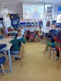 wnętrze czytelni biblioteki szkolnej, kilkoro uczniów siedzi przy stolikach i ogląda film o Sławoszu Uznańskim-Wiśniewskim, na ekranie postać polskiego astronauty