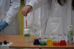 Uczennice klasy 7 prezentują "śnieżną burzę": W szklance wody znajduje się warstwa z pianki do golenia, na którą dziewczynki zakraplają po trochu kolorowe barwniki. Powstałe kropelki opadają na dno szklanki i tworzą piękny widok kolorowej, śnieżnej burzy.