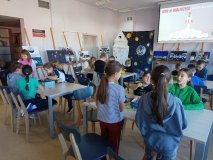 uczniowie siedzą przy stołach w grupkach po parę osób i zajęci są budowaniem z klocków LEGO