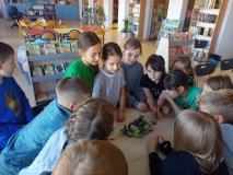 grupa uczniów stoi przy stole i opowiada całej klasie o swoim projekt zbudowanym z klocków LEGO