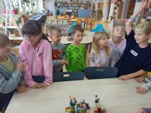 grupa uczniów stoi przy stole i opowiada całej klasie o swoim projekt zbudowanym z klocków LEGO