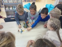grupa uczniów stoi przy stole i opowiada całej klasie o swoim projekt zbudowanym z klocków LEGO