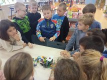 uczniowie zgromadzeni przy stole prezentują całej klasie skończony projekt z klocków LEGO