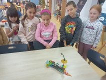 grupa uczniów stoi przy stole i opowiada całej klasie o swoim projekt zbudowanym z klocków LEGO