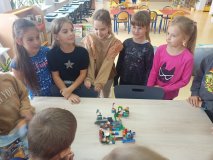  uczniowie w skupieniu słuchają kolegów, którzy prezentują swój projekt z klocków LEGO