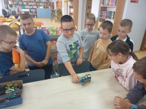 grupa uczniów stoi przy stole i opowiada całej klasie o swoim projekt zbudowanym z klocków LEGO