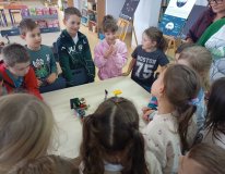 uczniowie zgromadzeni przy stole prezentują całej klasie skończony projekt z klocków LEGO