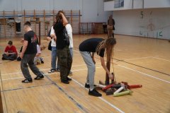 Foto. 3 W sali gimnastycznej chłopcy  pokonują rycerski tor przeszkód.  Przeszkody to drewniane kręgle i tyczki
