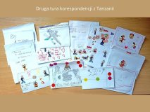 Kilkanaście kopert z kolorowym naklejkami leżą rozłożone na brązowym blacie biurka, u góry napis: Druga tura korespondencji z Tanzanii.