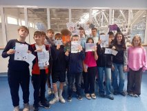 Grupa uczniów z klasy 6d stoi na korytarzu szkolnym i prezentuje listy otrzymane z Tanzanii.