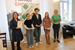 Drużyna SP 22 wraz z opiekunem pozuje do zdjęcia z panią Dyrektor Książnicy Płockiej. W rękach trzymają upominki oraz dyplom.