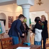 Drużyna z SP 22 rozwiązuje jedno z zadań turnieju: dwie osoby mają zawiązane oczy - jedna z nich trzyma białą kartkę, druga osoba trzyma ołówek i rysuje nim na kartce. Obok stoi trzecia osoba - chłopiec, wydaje komendy dziewczynce z ołówkiem.