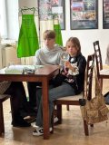 dwoje uczniów siedzi przy stoliku, uczennica trzyma przed sobą lupę powiększającą, przez którą spogląda