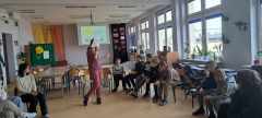 Uczniowie siedzący w kręgu uczestnicą w zajęciach.