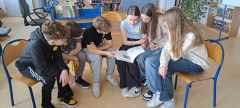 Grupa uczniów czyta książki przygotowane do zajęć.