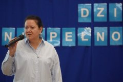 Pani Alicja Wojda i pani Agnieszka Sołtysiak, prowadzące apel z okazji Święta Osób z Niepełnosprawnościami, znajdują się na tle dekoracji z napisem 3 GRUDNIA MIĘDZYNARODOWY DZIEŃ OSÓB Z NIEPEŁNOSPRAWNOŚCIAMI.