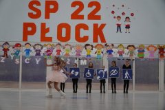 Prezentacja układu tanecznego na forum szkoły. Tancerki, w swojej choreografii, wykorzystują plansze prezentujące rożne rodzaje niepełnosprawności.